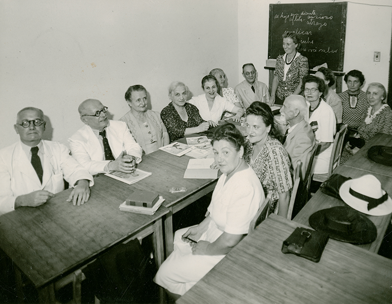 Einwanderer beim Portugiesisch-Unterricht. Wenige konnten sich auf die Auswanderung vorbereiten, auch weil sie nur mit dem Vorwand als Touristen einreisen dürfen. Die União wurde 1937 gegründet, um juristische Betreuung, Unterkunftssuche, Sprachunterricht und Hilfeleistung anzubieten.